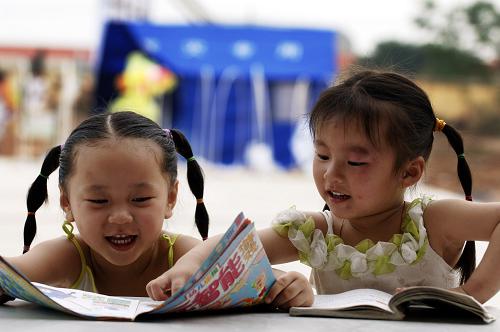 2008年5月31日,四川德陽的小朋友張雨梅(左)與涂齡文在安置點看圖書。她們將在安置點的帳篷里度過一個特別的兒童節(jié)。 新華社記者李健攝(資料照片)