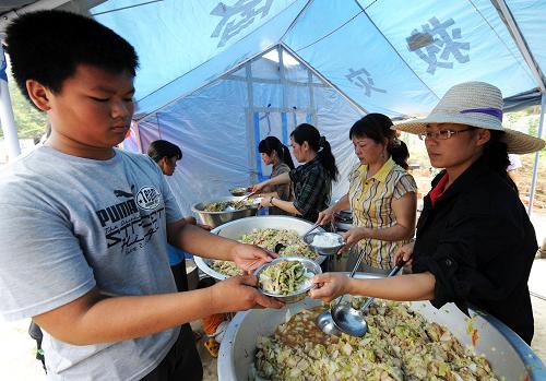6月5日,在廣西來(lái)賓市良江鎮(zhèn)吉利村吉利小學(xué)安置點(diǎn)內(nèi),村民在領(lǐng)午餐。 6月3日,廣西來(lái)賓市良江鎮(zhèn)吉利村出現(xiàn)地陷地質(zhì)災(zāi)害,在村邊的一座山下形成了4個(gè)巨坑,地陷造成當(dāng)?shù)胤课輭w出現(xiàn)開裂、傾斜、倒塌現(xiàn)象,并波及鄰近的山背屯和一座小型水庫(kù),當(dāng)?shù)攸h委、政府及時(shí)將吉利村委的吉利屯和山背屯137戶615位村民妥善安置到安全地帶。 新華社記者李斌攝