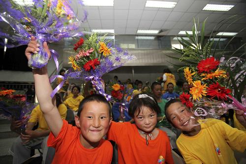 6月30日,來自玉樹的兒童開心地舉起北京市海淀外國語實驗學校學生獻上的鮮花。 當日,中華少年兒童慈善救助基金會在北京市海淀外國語實驗學校舉行“玉樹百名兒童休養(yǎng)營”開營儀式。剛剛抵達北京的第二批77名玉樹兒童與先前抵京的23名孩子一起參加了活動。孩子們將在兩個月時間里接受心理疏導、情感撫慰,并參加豐富多彩的文化活動。 新華社發(fā)(陳曉根 攝)