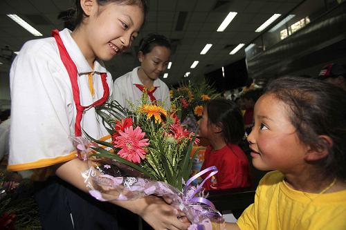 6月30日,北京市海淀外國語實驗學校的學生向玉樹兒童獻上鮮花。 當日,中華少年兒童慈善救助基金會在北京市海淀外國語實驗學校舉行“玉樹百名兒童休養(yǎng)營”開營儀式。剛剛抵達北京的第二批77名玉樹兒童與先前抵京的23名孩子一起參加了活動。孩子們將在兩個月時間里接受心理疏導、情感撫慰,并參加豐富多彩的文化活動。 新華社發(fā)(陳曉根 攝)