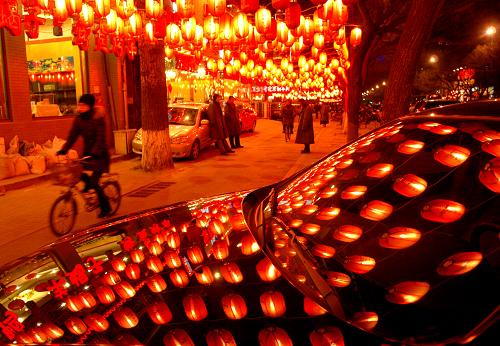 2月12日晚,市民走在北京一條掛滿紅燈籠的街道上,??吭诮诌叺钠囓嚿砩嫌持诸^懸掛的紅燈籠。農(nóng)歷虎年春節(jié)將至,京城一派喜氣洋洋,到處充滿了濃郁的祥和氣氛。新華社發(fā)(李文明 攝)