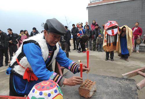 2月13日,在邛崍市南寶山永久安置點(diǎn),一位羌族老人在舞獅前敬拜天地。新華社記者 陳燮 攝