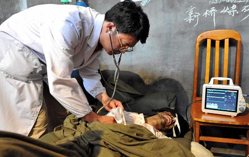 7月13日,在貴州晴隆透水事故救援現(xiàn)場,貴州省衛(wèi)生廳派出的專家——貴陽醫(yī)學(xué)院附屬醫(yī)院的鄧開盛(左)正在給被困25天后獲救的礦工王礦委檢查。新華社記者 楊楹 攝