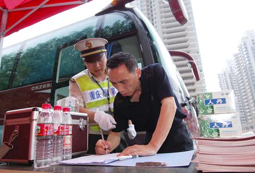 7月16日,重慶高速公路執(zhí)法支隊四大隊的一名執(zhí)法人員在指導客運車輛駕駛員填寫安全登記表格。新華社記者 劉潺 攝