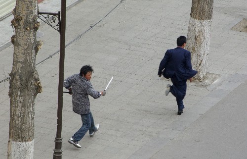 這張路透社播發(fā)的照片顯示,3月14日,在拉薩市,一名不法分子手持長刀追趕行人。新華社發(fā)