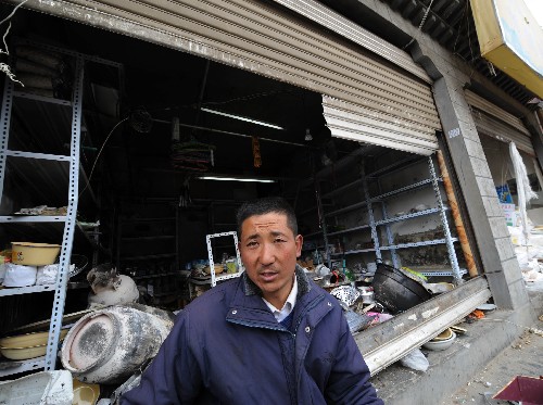 在拉薩市藏?zé)崮下?,從青海來拉薩做生意的馬么乃站在他被不法分子損毀的小店前(3月16日攝)。 新華社記者 覺果 攝