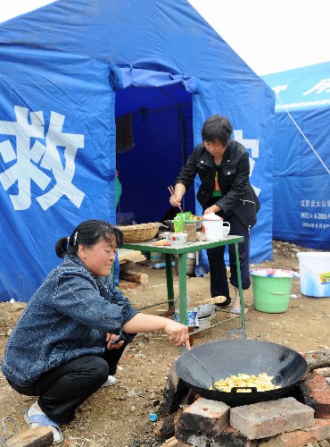 5月21日,在四川省北部的青川縣木魚鎮(zhèn),兩名當?shù)厝罕娬谧鲲?。連日來,四川汶川地震的重災區(qū)青川縣的各族群眾積極應對災情,化悲痛為力量,在黨和政府的關心及社會各界的幫助下努力開展自救工作。 新華社記者 藺以光 攝