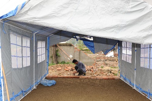 5月21日,在四川省北部的青川縣木魚鎮(zhèn),一名當?shù)厝罕娬跍蕚浯罱◣づ?。連日來,四川汶川地震的重災區(qū)青川縣的各族群眾積極應對災情,化悲痛為力量,在黨和政府的關心及社會各界的幫助下努力開展自救工作。 新華社記者 藺以光 攝