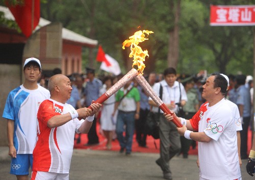 7月2日,火炬手馮世陽(右)與火炬手喬占山進行交接。當(dāng)日,北京奧運會圣火在延安傳遞。 新華社記者邢廣利攝