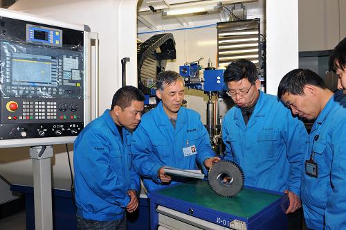 這是秦川機床工具集團有限公司研究院副院長王俊嶺(左二)和院里技術(shù)人員研究分析磨削誤差產(chǎn)生的原因和消除方法(12月12日攝)。新華社記者 何俊昌 攝