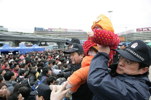 2月1日,鐵路公安特警從人群中接過小孩。2008年1月,我國南方遭遇了歷史上罕見的持續(xù)低溫、雨雪冰凍惡劣天氣。電網(wǎng)破壞,鐵路中斷。時值春節(jié)前夕,廣州火車站人流如潮水般涌動。短短幾天時間,大量旅客滯留車站,最多時達到約80萬人。緊急時刻,鐵道部公安局應急指揮部在廣州站設立。一聲令下,全國鐵路公安迅速調(diào)集3000民警支援廣州。其中,一支由500余名精英組成的特警隊尤為引人注目。這些隊員來自哈爾濱、沈陽、北京、上海、鄭州、西安等15個鐵路公安局的23支特警支隊。從1月30日到2月6日,八天八夜,他們始終堅守在廣州站廣場,哪里最危險哪里就有他們的身影!哪里最困難哪里就有他們堅韌挺拔的身軀!在風雪中,他們就像一堵沖不垮的“墻”,維護車站安全秩序,引導旅客進站乘車。新華社發(fā)(劉愛萍 攝)