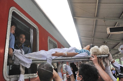 5月19日,醫(yī)療人員在綿陽火車站將一名地震傷員抬上火車。為使地震傷員得到及時治療、緩解災區(qū)醫(yī)療資源緊張局面,目前,有關部門正在轉移部分地震傷員到重慶等地的醫(yī)院接受治療。新華社記者 楊世堯 攝