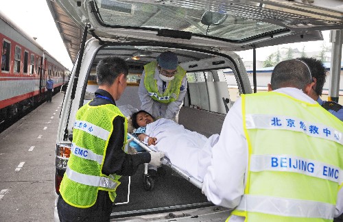 5月19日,醫(yī)療人員在綿陽火車站準備將一名地震傷員抬上火車。新華社記者 楊世堯 攝