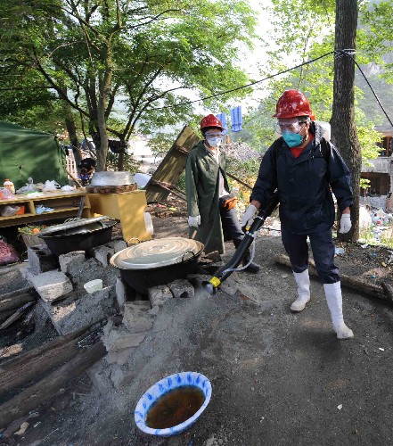 5月19日,四川自貢市疾病預(yù)防控制中心工作人員在地震重災(zāi)區(qū)北川縣的災(zāi)區(qū)群眾居住區(qū)噴灑消毒藥劑。新華社記者 陳樹根 攝