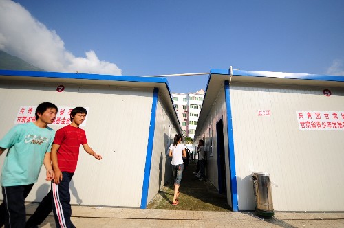 6月10日,在甘肅省文縣一中內(nèi)搭建的抗震中學(xué),幾名學(xué)生從活動(dòng)板房教室旁走過。甘肅省第一所抗震中學(xué)在文縣地震災(zāi)區(qū)投入使用。該中學(xué)共花費(fèi)資金178萬元,由60間活動(dòng)板房組成,每間活動(dòng)板房60平方米,可滿足全校3000余名學(xué)生上課。新華社記者 張錳 攝