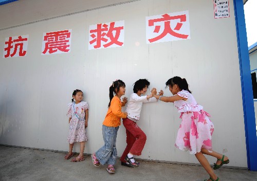 6月11日,隴南市文縣城關(guān)第二小學(xué)學(xué)生課間在活動板房旁玩耍。新華社記者 聶建江 攝