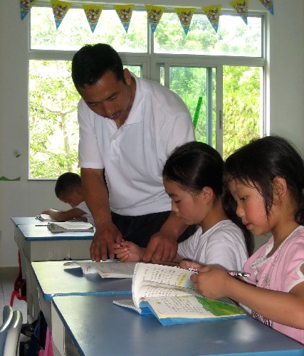 6月11日,校長朱金勇在深圳的新教室里給孩子們輔導(dǎo)。日前,來自四川汶川阿爾寨小學(xué)的84名羌族孩子和6名老師在廣東公安邊防七支隊深圳某駐地復(fù)課學(xué)習(xí)。邊防七支隊騰出了15間房子給師生們生活和學(xué)習(xí),明亮的教室和嶄新的課桌,讓孩子們有了一個良好的學(xué)習(xí)環(huán)境。新華社記者 陳曉建 攝