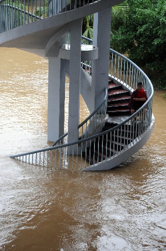 6月13日,柳江上漲的江水漫過沿江地段一座天橋的階梯,一位市民坐在階梯上。新華社發(fā)