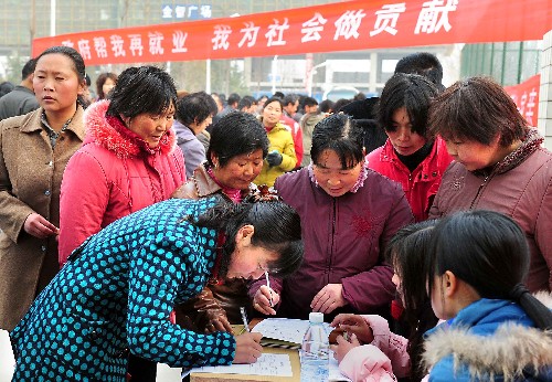 2月14日,幾位農(nóng)村婦女在一家招聘企業(yè)的攤點前填寫招聘表。新華社記者 王頌 攝