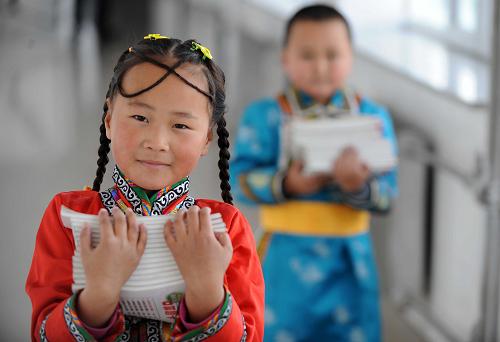 10月21日,內(nèi)蒙古錫林郭勒盟西烏珠穆沁旗蒙古小學(xué)一年級學(xué)生葛根其其格(左)幫全班同學(xué)取作業(yè)本。新華社記者 張領(lǐng) 攝