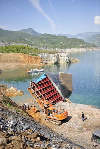 4月23日,事故滾裝船已呈近90度角側(cè)躺在岸邊水域,船身后半截在水下。 截至23日10時(shí),湖北巴東翻船事故已累計(jì)有5具遇難者遺體被打撈上岸,水下還有3具遺體得到初步定位,至少還有6名落水者失蹤。目前,有3支專(zhuān)業(yè)救撈隊(duì)伍在施救現(xiàn)場(chǎng)作業(yè),但是由于該滾裝船體積和自重都比較大,而清江流域水布埡大壩上游不具備大型救撈設(shè)備,加上事發(fā)地岸邊地形狹窄,大型作業(yè)尚未展開(kāi)。 4月21日5時(shí)30分左右,湖北巴東境內(nèi)清江上一艘滾裝船發(fā)生側(cè)翻事故,導(dǎo)致當(dāng)時(shí)船上14輛貨車(chē)落水,事發(fā)當(dāng)時(shí)至少14人下落不明。新華社記者 郝同前 攝