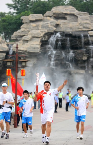 7月4日,火炬手齊大凱手持火炬?zhèn)鬟f。 新華社記者 邢廣利 攝