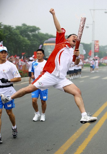 7月28日,火炬手鄭鵬手持火炬?zhèn)鬟f。當(dāng)日,北京奧運圣火在河南省安陽市傳遞。 新華社記者 邢廣利 攝