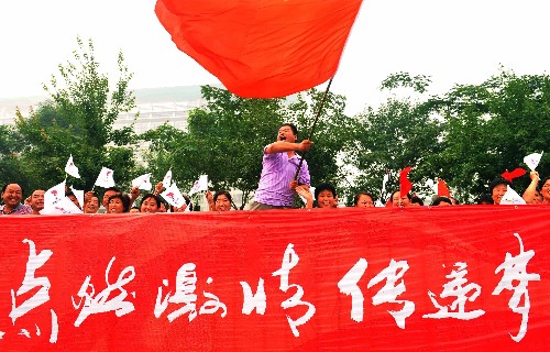 7月28日,一名觀眾揮舞旗幟為圣火傳遞加油。當(dāng)日,北京奧運圣火在河南省安陽市傳遞。 新華社記者 安治平 攝
