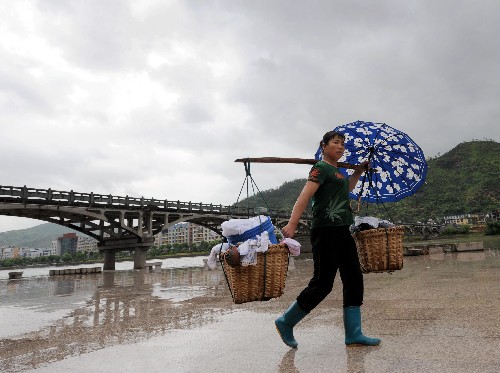 7月18日,福建福鼎市一位市民在冒雨轉(zhuǎn)移物品。福建省氣象臺(tái)最新消息,強(qiáng)熱帶風(fēng)暴“海鷗”于18日18時(shí)10分在福建霞浦縣長(zhǎng)春鎮(zhèn)登陸,中心氣壓988百帕,近中心風(fēng)力最大風(fēng)力10級(jí),風(fēng)速25米/秒。 新華社記者姜克紅攝