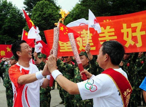 8月4日,火炬手謝勝和(左)將與下一棒火炬手胥懷君交接。當(dāng)日,北京奧運(yùn)圣火在四川省廣漢市三星堆博物館展示傳遞。 新華社記者劉力航攝