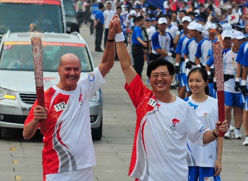 8月6日,火炬手楊元慶(右)與下一棒火炬手高斯帕(Gosper Richard kevan)交接后慶祝。當(dāng)日,北京奧運(yùn)圣火在北京市傳遞。 新華社記者安治平攝