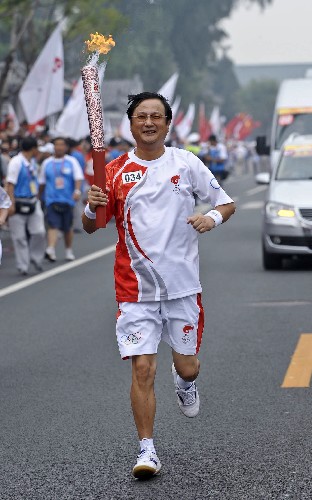8月6日,火炬手何寧手持火炬?zhèn)鬟f。當(dāng)日,北京奧運(yùn)圣火在北京市傳遞。 新華社記者戚恒攝