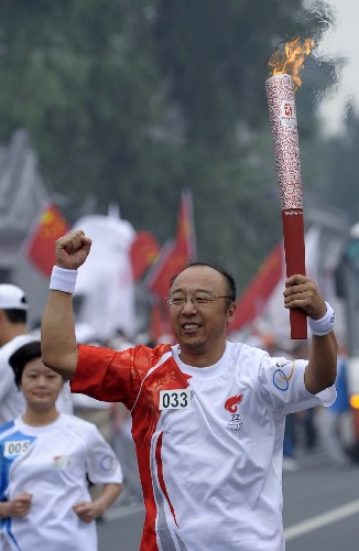 8月6日,火炬手孟令迪手持火炬?zhèn)鬟f。當(dāng)日,北京奧運(yùn)圣火在北京市傳遞。 新華社記者戚恒攝