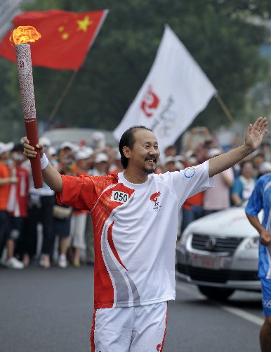 8月6日,火炬手騰格爾手持火炬?zhèn)鬟f。當(dāng)日,北京奧運(yùn)圣火在北京市傳遞。 新華社記者戚恒攝