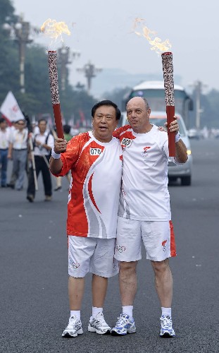 8月6日,火炬手伊武·拉赫齊(右)與下一棒火炬手宋泰山交接后慶祝。當(dāng)日,北京奧運(yùn)圣火在北京市傳遞。 新華社記者戚恒攝