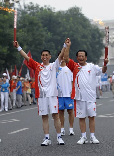 8月6日,火炬手張百發(fā)(右)與下一棒火炬手左芷津交接后慶祝。當(dāng)日,北京奧運(yùn)圣火在北京市傳遞。 新華社記者戚恒攝