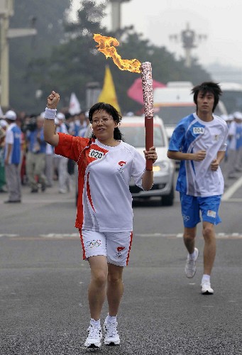 8月6日,火炬手趙曉霞手持火炬?zhèn)鬟f。當(dāng)日,北京奧運(yùn)圣火在北京市傳遞。 新華社記者戚恒攝