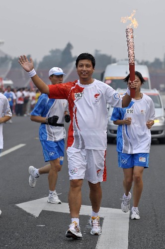 8月6日,火炬手魯向東手持火炬?zhèn)鬟f。當(dāng)日,北京奧運(yùn)圣火在北京市傳遞。 新華社記者戚恒攝