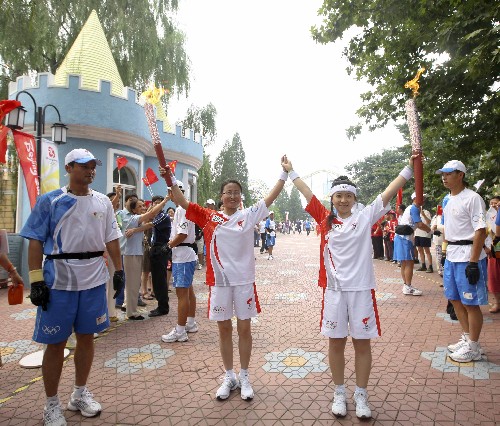 8月6日,火炬手李文(前左二)與姜曉燕交接。當(dāng)日,北京奧運圣火在北京市傳遞。 新華社記者邢廣利攝