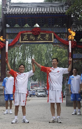 8月7日,火炬手羅峰(右)與下一棒火炬手趙喜吉交接后慶祝。當(dāng)日,北京奧運(yùn)圣火在北京市傳遞。 新華社記者戚恒攝