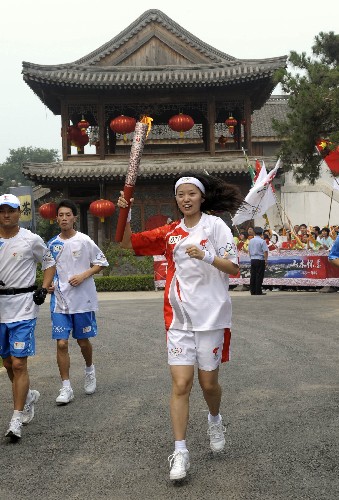 8月7日,火炬手惠尚懿手持火炬?zhèn)鬟f。當(dāng)日,北京奧運(yùn)圣火在北京市傳遞。 新華社記者戚恒攝