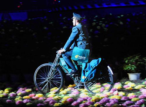 4月9日,在洛陽(yáng)新區(qū)體育場(chǎng),一位“郵遞員”騎著自行車(chē)從牡丹花前經(jīng)過(guò)。 當(dāng)晚,中國(guó)2009世界集郵展覽暨第27屆洛陽(yáng)牡丹花會(huì)開(kāi)幕式在洛陽(yáng)新區(qū)體育場(chǎng)舉行。開(kāi)幕式上的大型文藝晚會(huì),將世界郵展的國(guó)際性、包容性和古都洛陽(yáng)的地域特色、文化魅力有機(jī)地結(jié)合起來(lái),完美地詮釋了“郵傳萬(wàn)家,花和天下”的主題。 新華社記者王頌攝