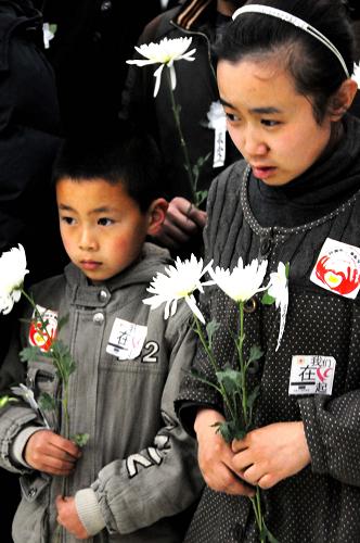 4月17日,兩位小朋友手持鮮花為阿福默默祈禱。 當(dāng)日22點(diǎn)45分,青海玉樹地震中舍身救人不幸罹難的香港義工黃福榮遺體運(yùn)抵青海省會(huì)西寧,各界群眾在臨近的互助土族自治縣神安殯儀館為黃福榮舉行了簡(jiǎn)單肅穆的追悼會(huì)。在這里黃福榮將告別這片他拋灑鮮血和生命的高原熱土,于18日“回歸”家鄉(xiāng)香港。 新華社記者 陳國(guó)洲 攝