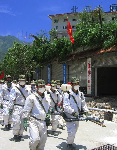 7月5日,幾名防化兵從北川縣城廢墟前走過。 新華社記者 劉思揚(yáng) 攝