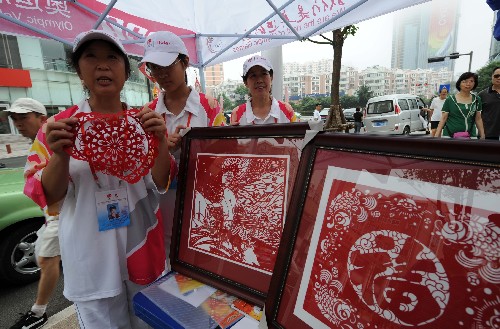 7月28日,奧帆志愿者、山東省剪紙協(xié)會副秘書長趙玉華(左一)在奧運(yùn)志愿服務(wù)站介紹中國剪紙藝術(shù)。新華社記者 宋振平 攝