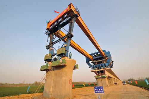 這是我國(guó)JQ900B型架橋機(jī)在進(jìn)行整孔箱梁架設(shè)(4月9日攝)。4月8日,承擔(dān)京滬高速鐵路土建工程二標(biāo)段施工任務(wù)的中鐵一局集團(tuán),在德禹大橋、禹濟(jì)大橋和黃河大橋架梁施工中,再創(chuàng)日架整孔箱梁20孔新高,一舉刷新了由他們自己日前創(chuàng)造的日架整孔箱梁16孔的高產(chǎn)成績(jī)。截止到4月8日,中鐵一局集團(tuán)已順利完成京滬高速鐵路整孔箱梁架設(shè)473孔,為京滬鐵路早日通車奠定了堅(jiān)實(shí)的基礎(chǔ)。新華社記者 何俊昌 攝