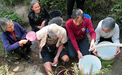 9月23日,邵陽(yáng)縣南山村村民在探井隊(duì)勘查出的山泉水源處接水。湖南省邵陽(yáng)縣至今已連續(xù)50余天晴熱無(wú)雨,旱情仍在持續(xù)。當(dāng)?shù)赜嘘P(guān)部門(mén)組織500余個(gè)掘井隊(duì)與2000多名機(jī)關(guān)干部深入鄉(xiāng)村,幫助村民勘探水源,打井抗旱。該縣目前已掘井近3萬(wàn)口,并調(diào)集運(yùn)水車(chē)為旱區(qū)群眾送水。 新華社發(fā)(李?lèi)?ài)民 攝)