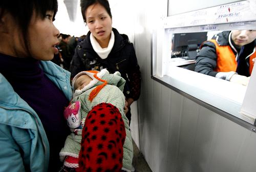 1月28日,旅客鐘燕燕(左一)懷抱女兒在上?;疖囌緶?zhǔn)備購買2月7日上海至成都的火車票時(shí),被告知票已售完。新華社記者 陳飛 攝
