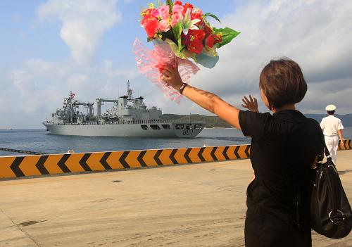 3月4日,一名護(hù)航編隊(duì)軍官家屬手持鮮花在碼頭送行。新華社記者 查春明 攝