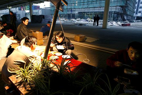 4月11日,來自湖北黃岡的綠化裝飾工汪家林(右二),正和工友在世博園高架景觀道路下吃午餐。新華社記者陳飛攝
